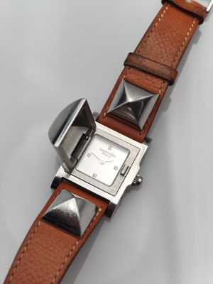 gros plan d'une montre sur une surface blanche avec un bracelet marron