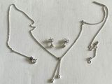 un gros plan d'un ensemble composé d'un collier et de boucles d'oreilles posé sur une surface blanche