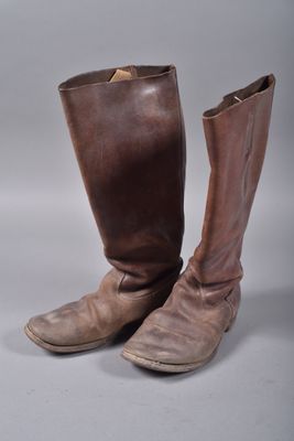 une paire de bottes en cuir marron posées sur une surface blanche