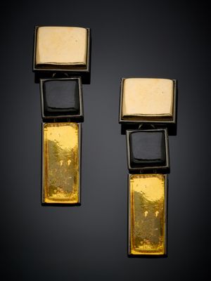 deux boucles d'oreilles dorées et noires de forme carrée sur fond noir