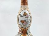 a white vase with a gold and red decoration on it