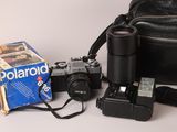 a black bag, a camera, and a box of polaroid