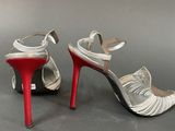 silver and red high heeled sandals on a grey surface