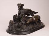statue en bronze représentant un chien et deux chiens sur un rocher