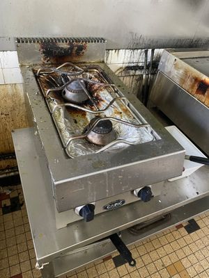une cuisinière sale dans une cuisine sale, avec des casseroles et des poêles posées dessus