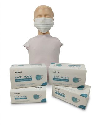 une personne portant un masque à côté de trois boîtes de masques jetables