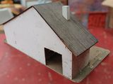 a small white house with a chimney on a red table