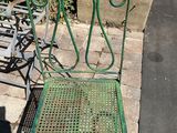 a green metal chair sitting on the sidewalk next to a bench