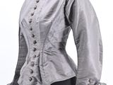 a close up of a mannequin wearing a gray jacket with ruffles