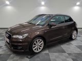 L'Audi marron est garée dans une grande pièce au sol carrelé.