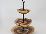 a three tiered wooden plate with a metal stand