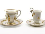 two cups and saucers are sitting on a white surface