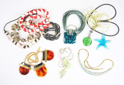 de nombreux colliers et bracelets disposés sur une surface blanche