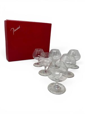 several empty wine glasses and a red box on a white surface