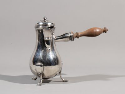 a silver coffee pot with a wooden handle sitting on top of a table