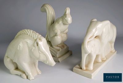 Deux statues d'animaux sont posées l'une à côté de l'autre sur une surface blanche.