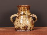 a brown vase sitting on a table with a black background