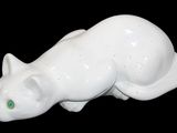 une figurine de chat blanc aux yeux verts sur fond noir