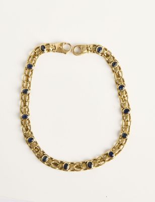 Gros plan sur un bracelet en or orné de pierres bleues