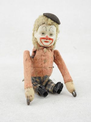 une petite poupée assise par terre, coiffée d'un chapeau
