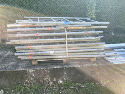 a pile of pipes sitting on the ground next to a chain link fence