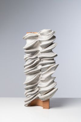 un gros plan d'une sculpture posée sur une table, sur fond gris