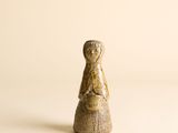 figurine en bois représentant une femme tenant un panier, posée sur une surface blanche