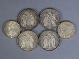 six different types of silver coins on a blue surface