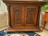 an old wooden cabinet sitting on top of a rug in front of a window