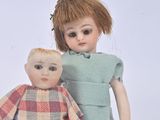 two dolls standing next to each other on a white surface