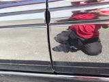 a reflection of a man kneeling on the ground next to a car