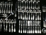 a lot of silver spoons and forks laid out on a table
