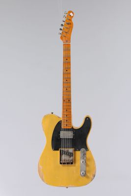 une guitare électrique suspendue à une ficelle sur un mur blanc