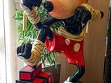 statue of mickey mouse holding a baseball bat in front of a window