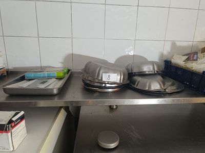 several pans and pans on a stainless steel shelf in a kitchen