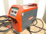 an orange and black welding machine sitting on top of a wooden table