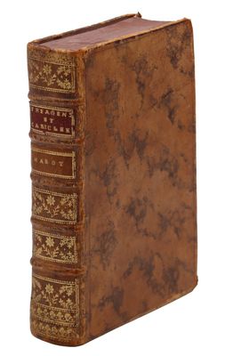 un vieux livre à la couverture brune posé sur une surface blanche