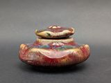 a red and yellow vase with a lid on a table