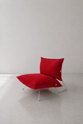 une chaise rouge placée dans une pièce blanche, près d'une fenêtre