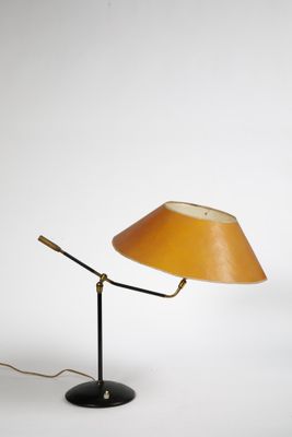 une lampe jaune posée sur un pied noir, avec un fond blanc