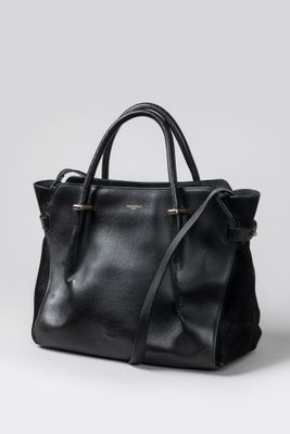 un sac à main noir posé sur une surface blanche