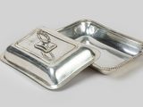 two silverplated dishes with handles and handles on a white surface