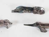 three metal animal figurines sitting on a white surface