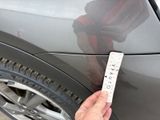 a hand that is holding a ticket near a car