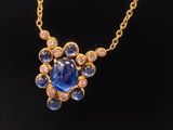 a gold necklace with a blue sapphire and diamonds