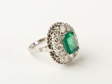 a close up of a ring with an emerald stone surrounded by diamonds