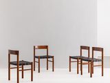 un ensemble de quatre chaises aux assises en cuir noir dans une pièce blanche