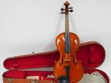 un vieux violon repose dans son étui, posé sur une surface blanche