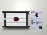 a close up of a red ruby stone in a white box