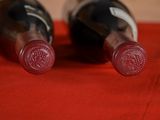 two bottles of wine sitting on a red cloth